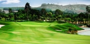 Approach to a green at Barcelona Valley Lake Course, with bunkers, water on the right and hills beyond.
