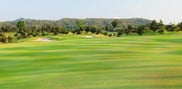 Broad fairway on the 15th hole at Barcelona Valley Mountain Course, with sand bunkers, scattered trees and wooded hills beyond.